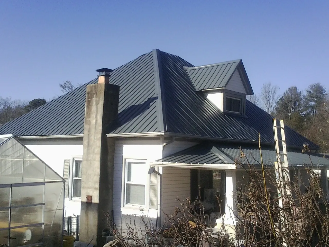 Dark blue standing seam metal roof on a white farmhouse with dormer — Slate & Tile Roof Repair by Roofing Brothers in Oxford