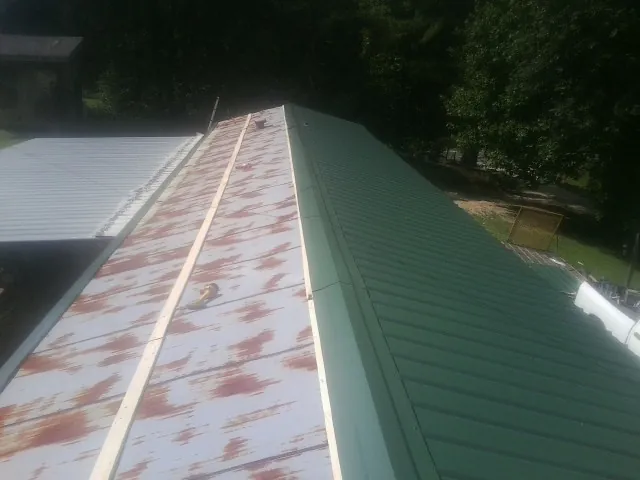 Old rusted panels beside newly installed green metal roofing — Wind Damage Roof Repair by Roofing Brothers in Oxford